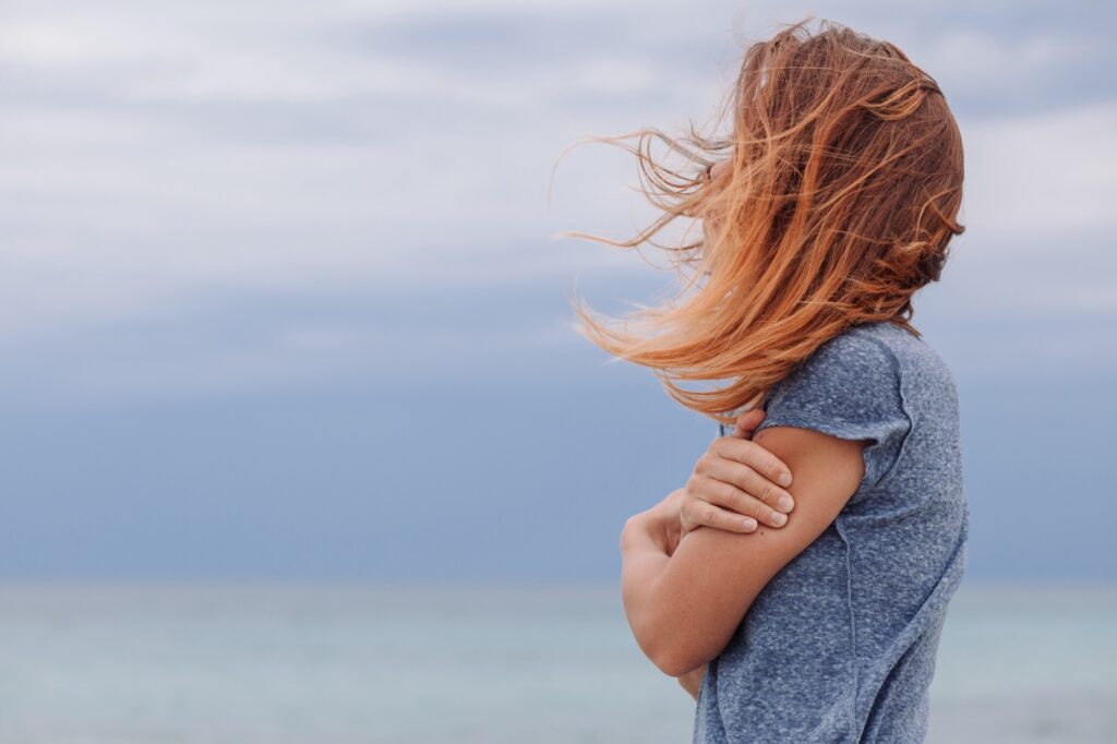 Infertility Counseling and Third-Party Reproduction​ page image of woman hugging herself and hair swept by wind